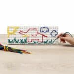 a child drawing with colored threads on a white board