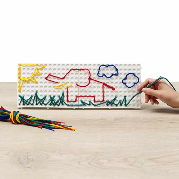 a child drawing with colored threads on a white board
