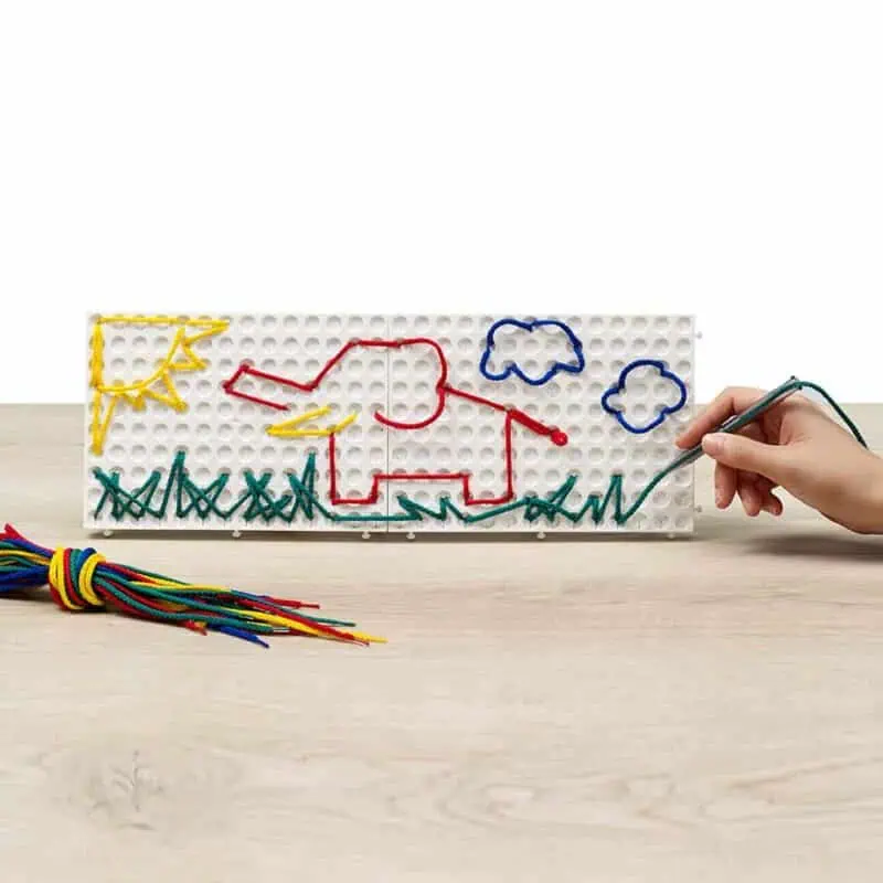 a child drawing with colored threads on a white board