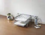 a metal tray with papers and a clock on a wood surface