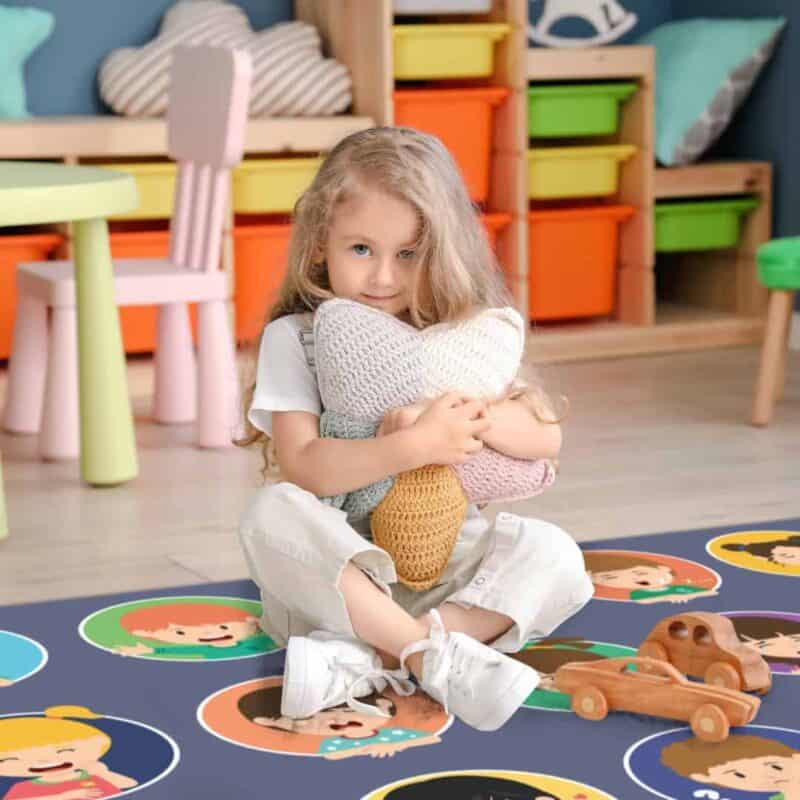 A girl sitting on the floor holding a stuffed animal