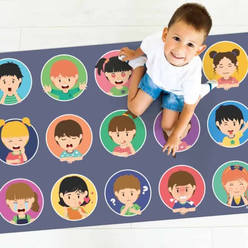 A child sitting on a rug with cartoon faces