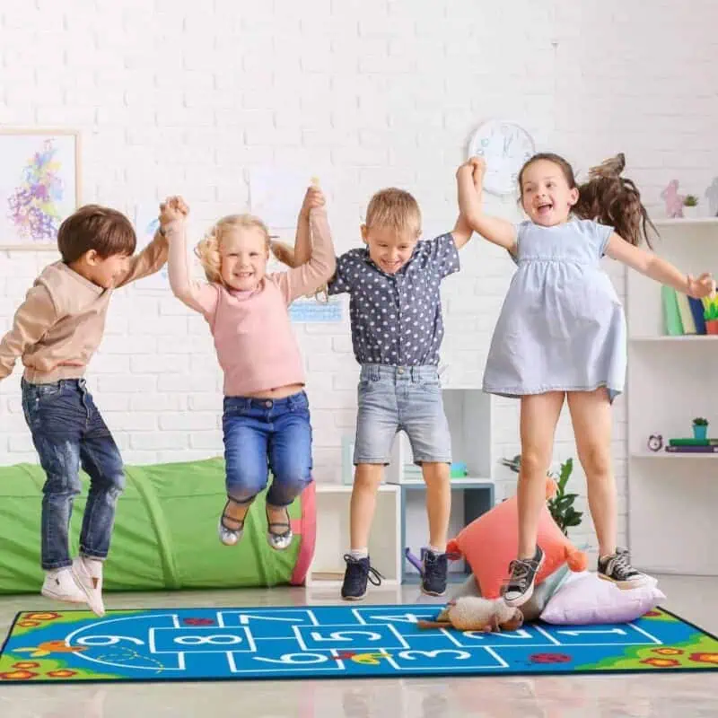 a group of kids jumping on a rug