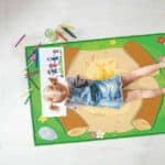 a girl lying on a rug with crayons
