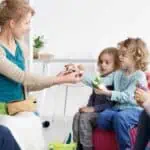 a woman giving a small mushroom to a group of children