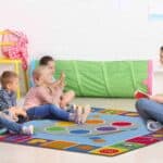 a woman sitting on a rug with children