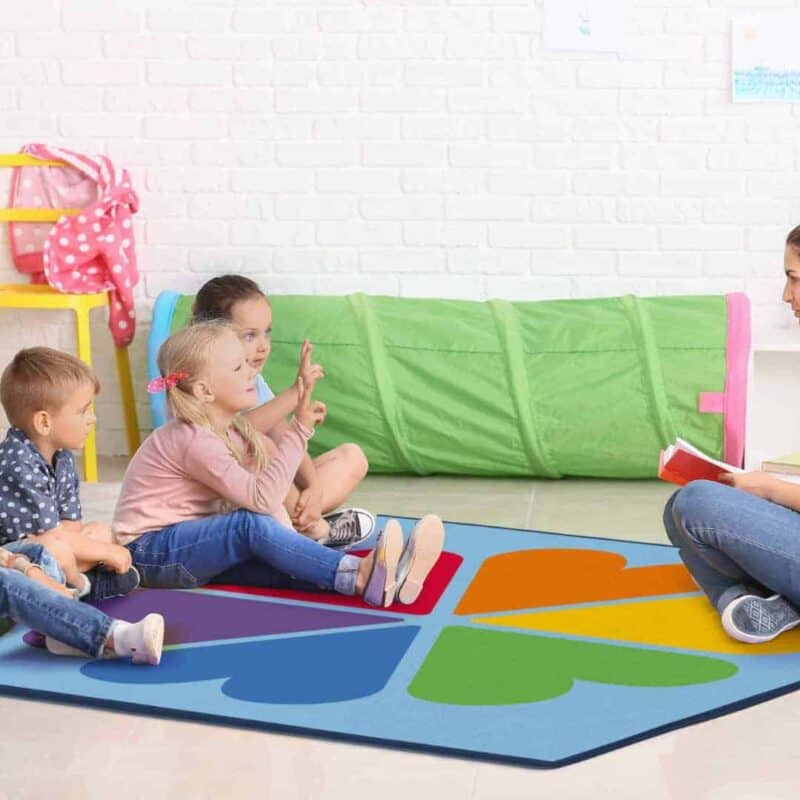 A woman sitting on a rug with children