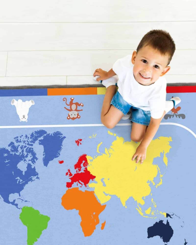 A child sitting on a rug with a map of the world