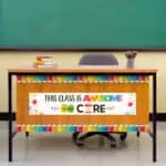 Bright classroom desk with colorful educational decor and motivational sign for students.