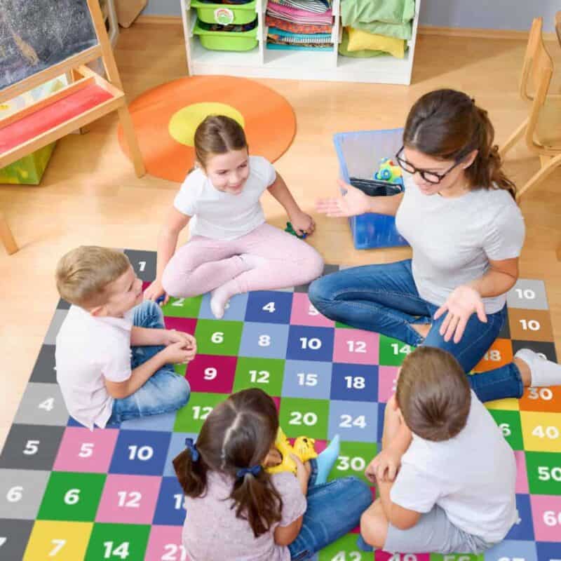 A group of children sitting on a rug in a classroom
