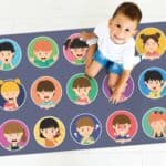 a child sitting on a rug with cartoon faces