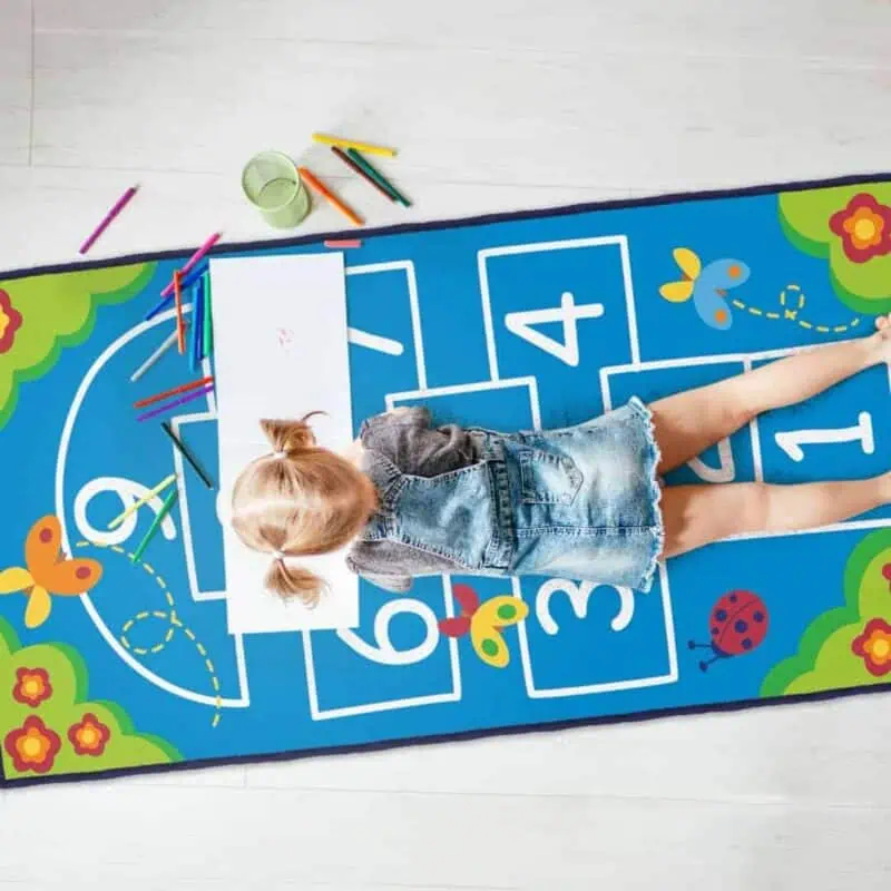 A girl lying on a rug with markers