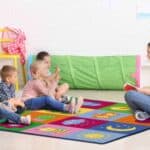 a woman sitting on a rug with children