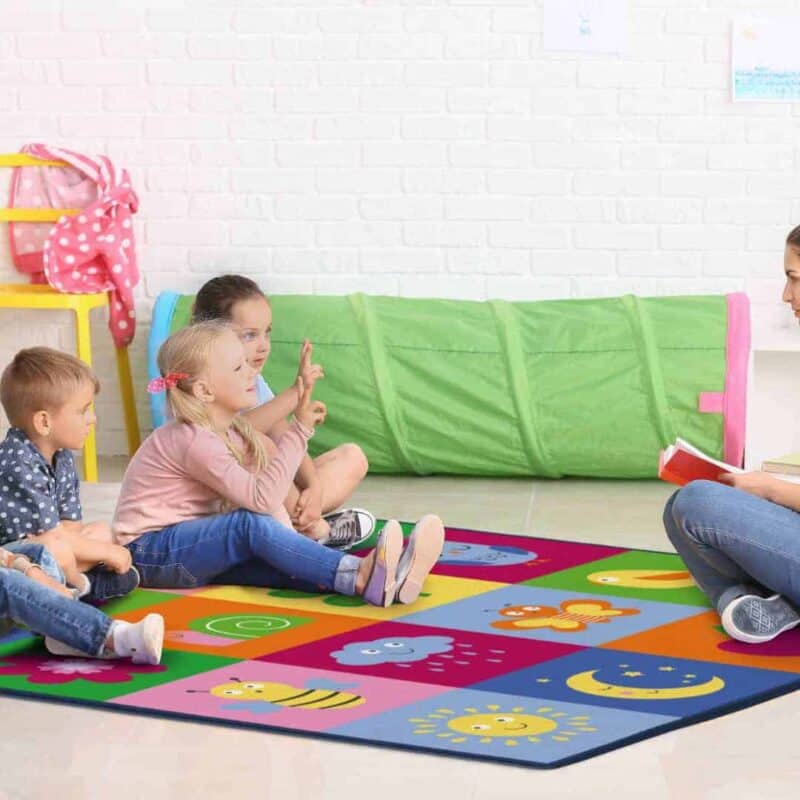 A woman sitting on a rug with children