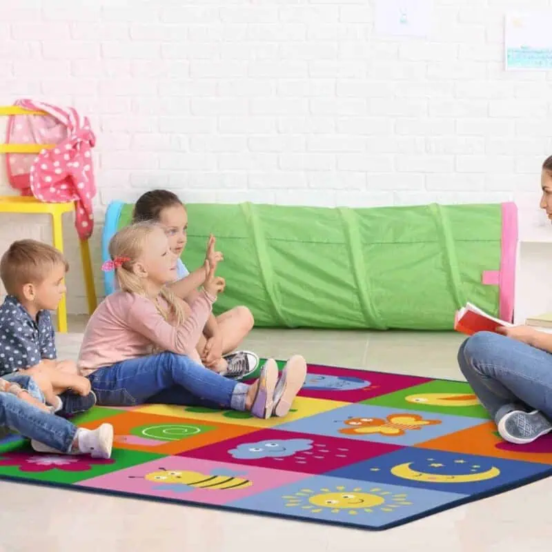 A woman sitting on a rug with children