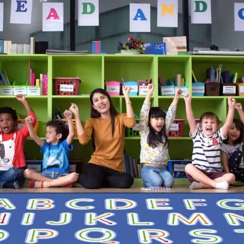 A group of children and a woman raising their hands