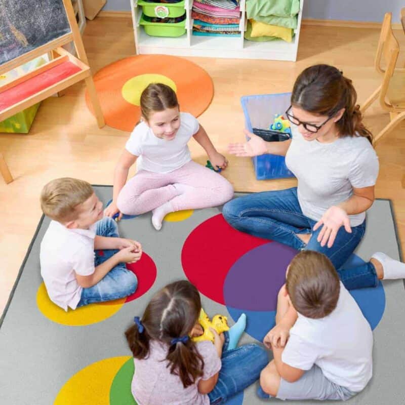 A group of children sitting on a rug in a classroom