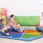 a woman sitting on a rug with children